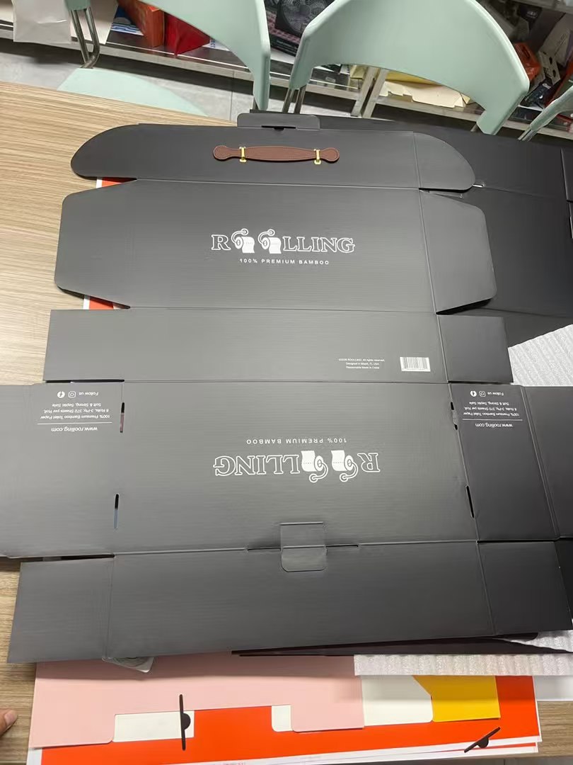 Unfolded black corrugated gift mailer showing the handle placement and locking tabs