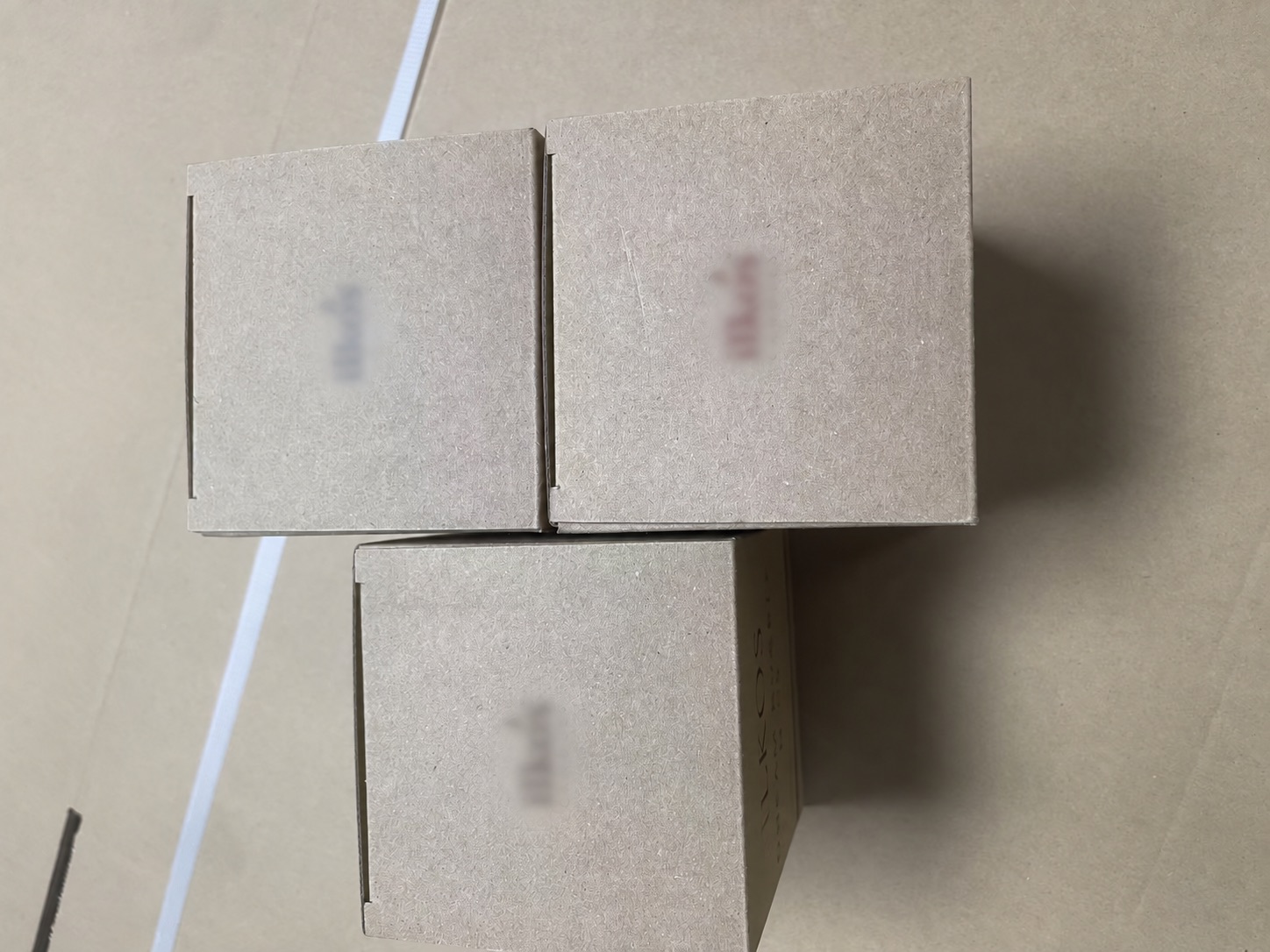 Three finished candle cartons in different fragrance colours, with customer branding blurred